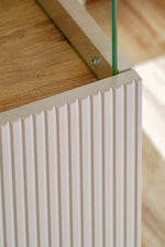 Display cabinet corner detail with ribbed white panel and metal hinge hardware
