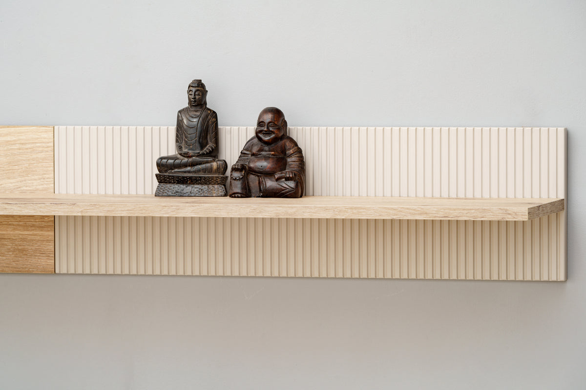 Wall-mounted slatted wood shelf with two figurines on top