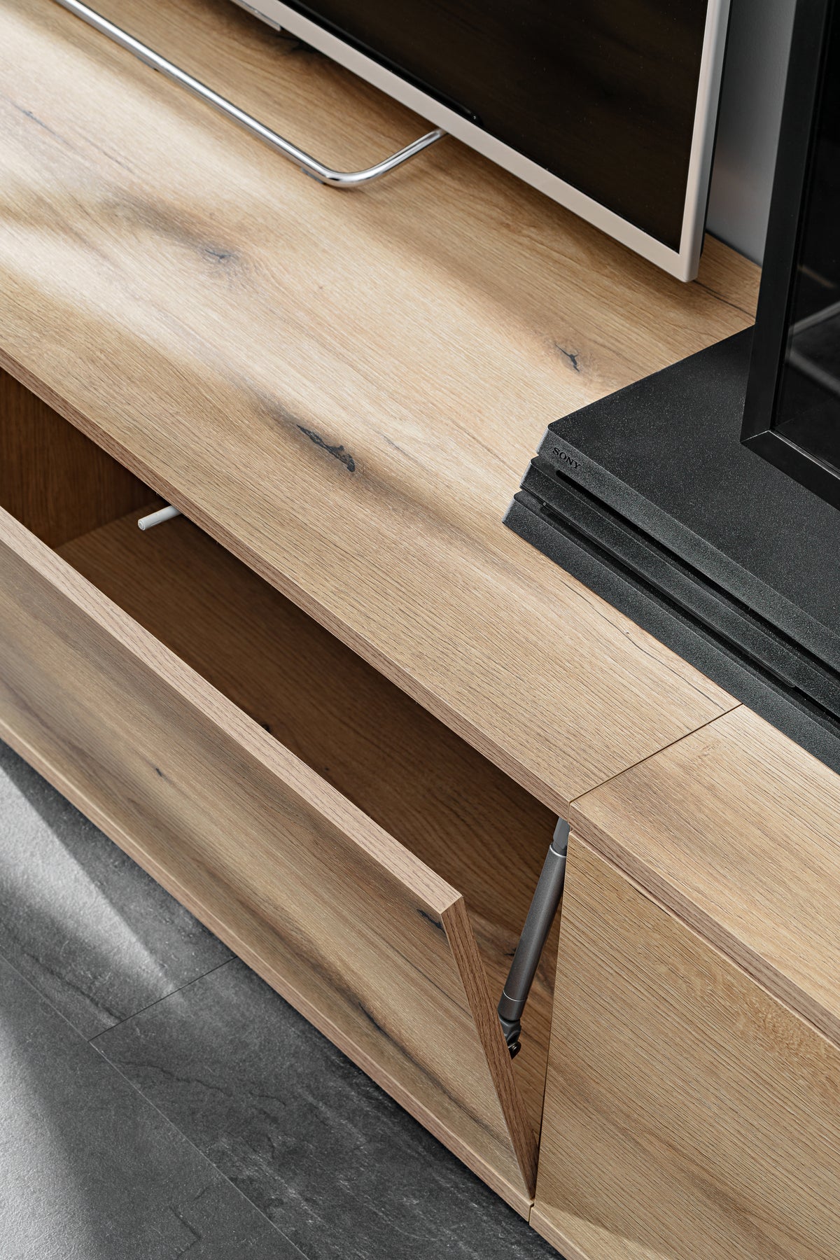 Drawer rail and sliding track detail on light wood wall unit with black side frame