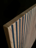 Black and oak bedside cabinet with vertical slat front, close-up corner detail