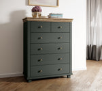 Dark green chest of drawers with light wood top and five drawers, round metal knobs.