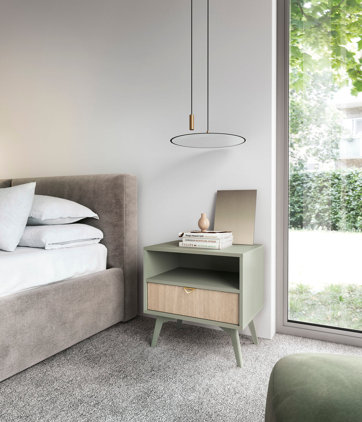 Olive green bedside table with open shelf and drawer beside a bed in natural light.