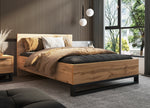 Wood bedside table with drawer and black base beside bed frame