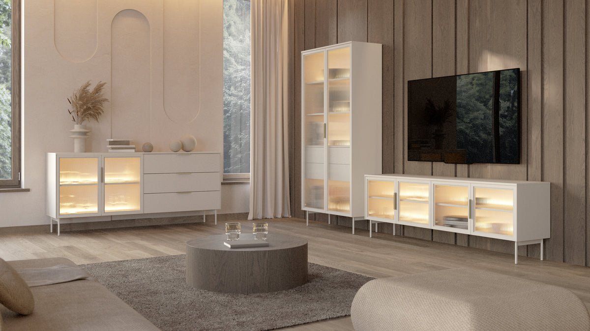 White freestanding TV cabinet with warm LED-lit glass doors and slim metal legs.