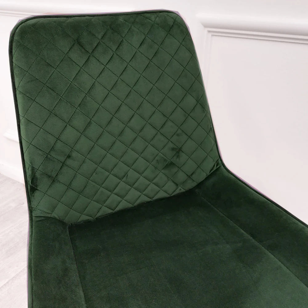 Green velvet dining chair with diamond-tufted back and curved arms; dark legs.