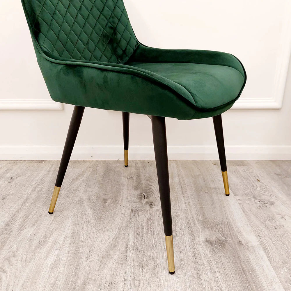 Green velvet dining chair with diamond-tufted back, curved armrests, and slim legs.