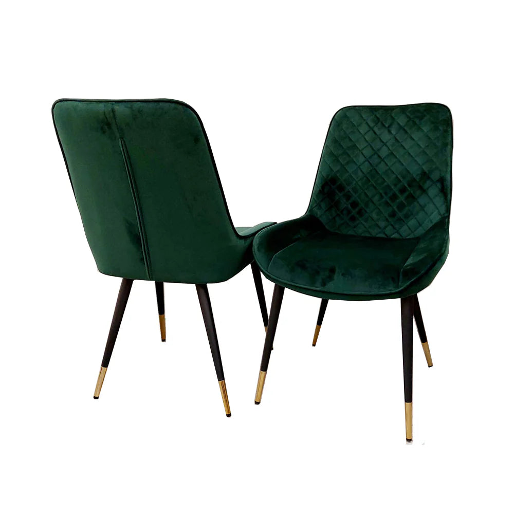 Set of two green velvet dining chairs with diamond-tufted backs and tapered legs.