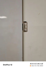 Wall panel edge with metal latch/hinge hardware on light backing