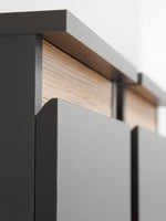 Close-up of TV wall unit edge: dark cabinet with light wood shelf detail