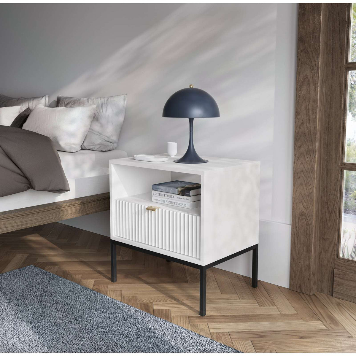 White bedside table in a living room, with ribbed drawer front and open shelf.