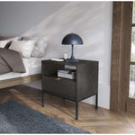 Dark gray bedside table in a living room, with ribbed drawer front and open shelf.