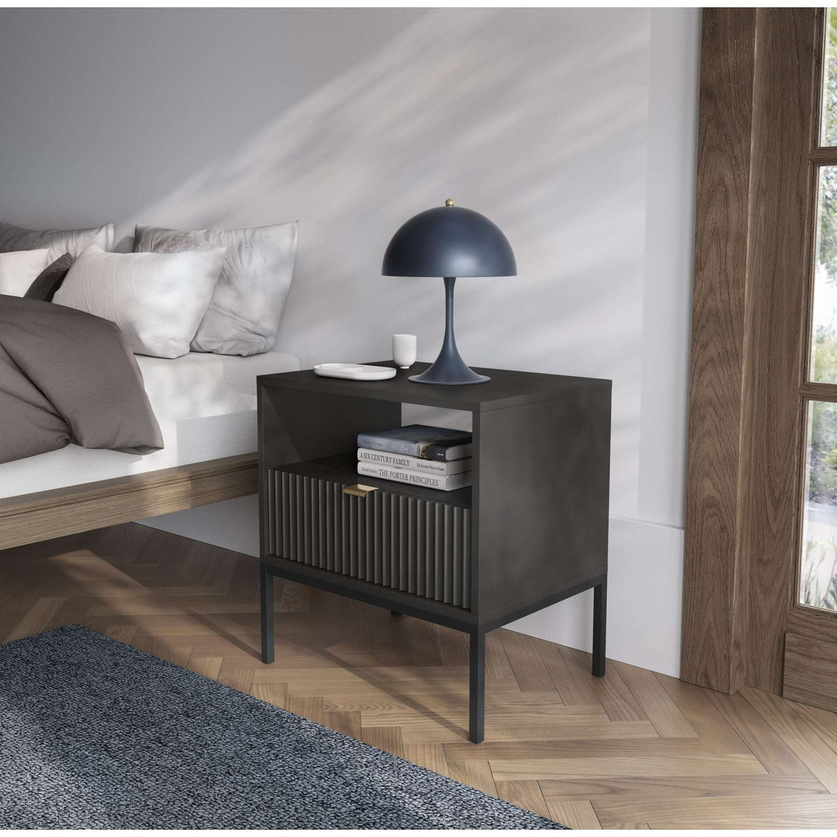Dark gray bedside table in a living room, with ribbed drawer front and open shelf.