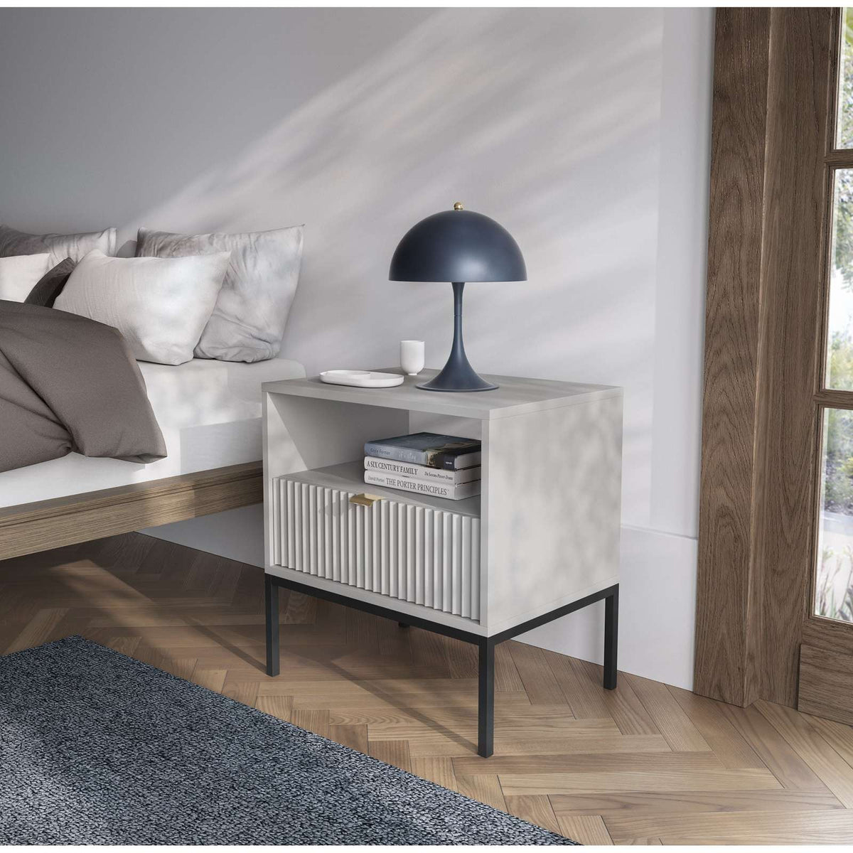 White bedside table in a living room, with ribbed drawer and open shelf.