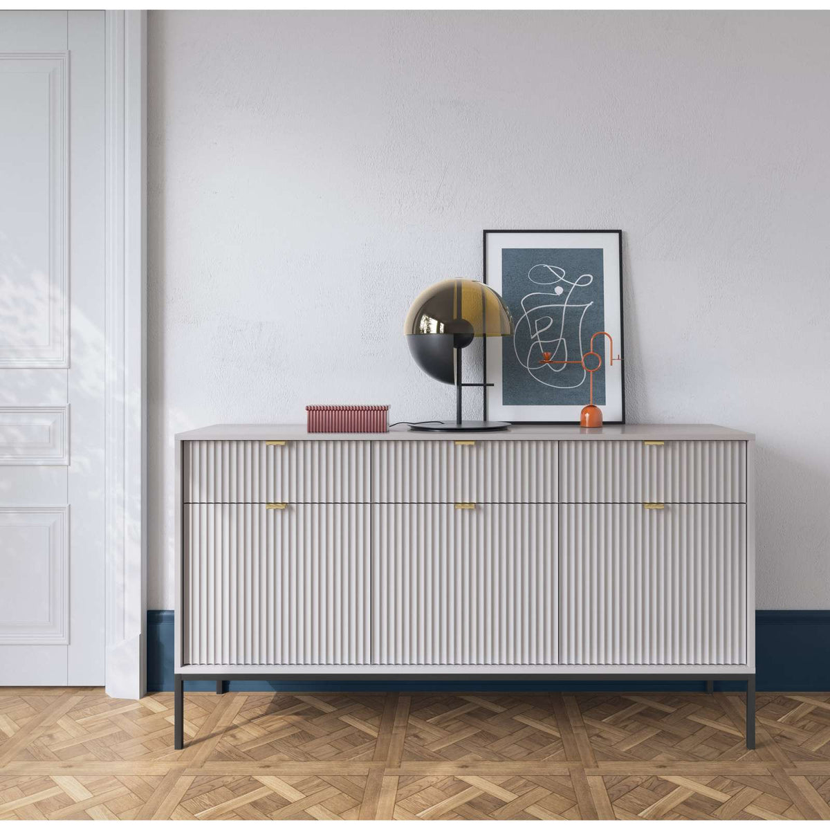 Light gray ribbed sideboard with gold bar handles and three doors, on black legs