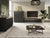 Black bedside cabinet with ribbed door and gold accent strip, coordinating media console nearby.