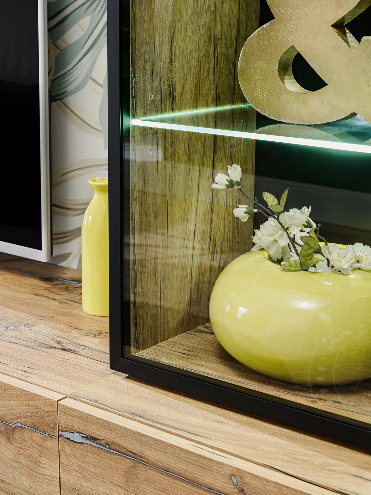Ray TV wall unit LED-lit glass cabinet with amber decorative vase and floral arrangement