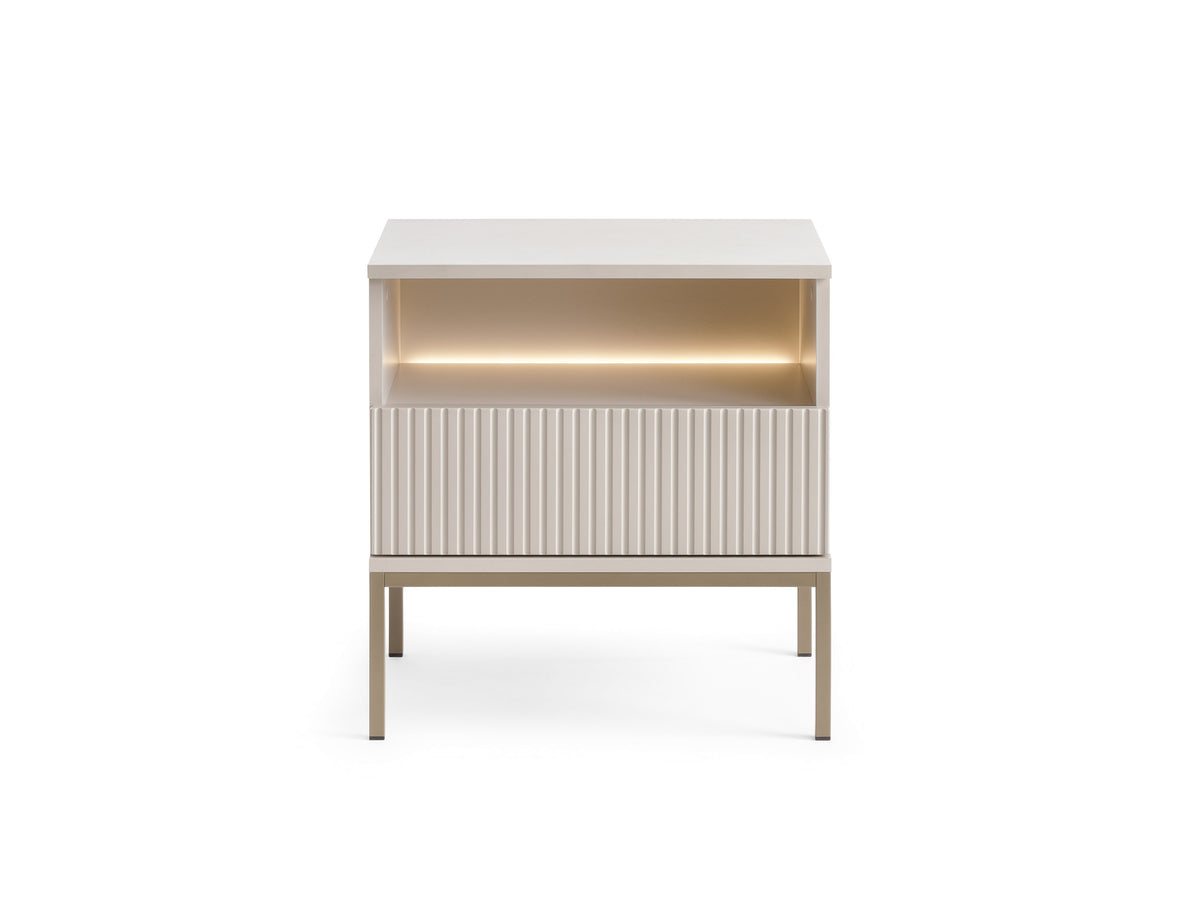 White bedside table with ribbed vertical drawer front and glowing open shelf
