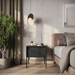 Black bedside table with ribbed drawer front, flat top, and slim legs