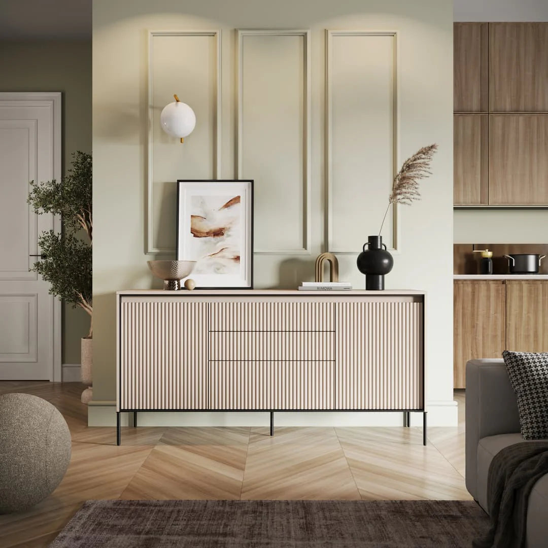 Beige sideboard with ribbed doors and three drawer fronts, two-door storage.