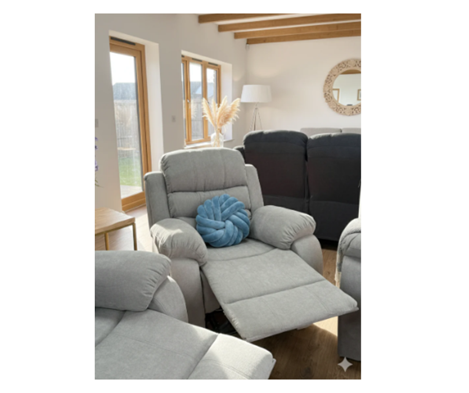 Gray fabric recliner with blue throw pillow, side view, padded arms and seat.