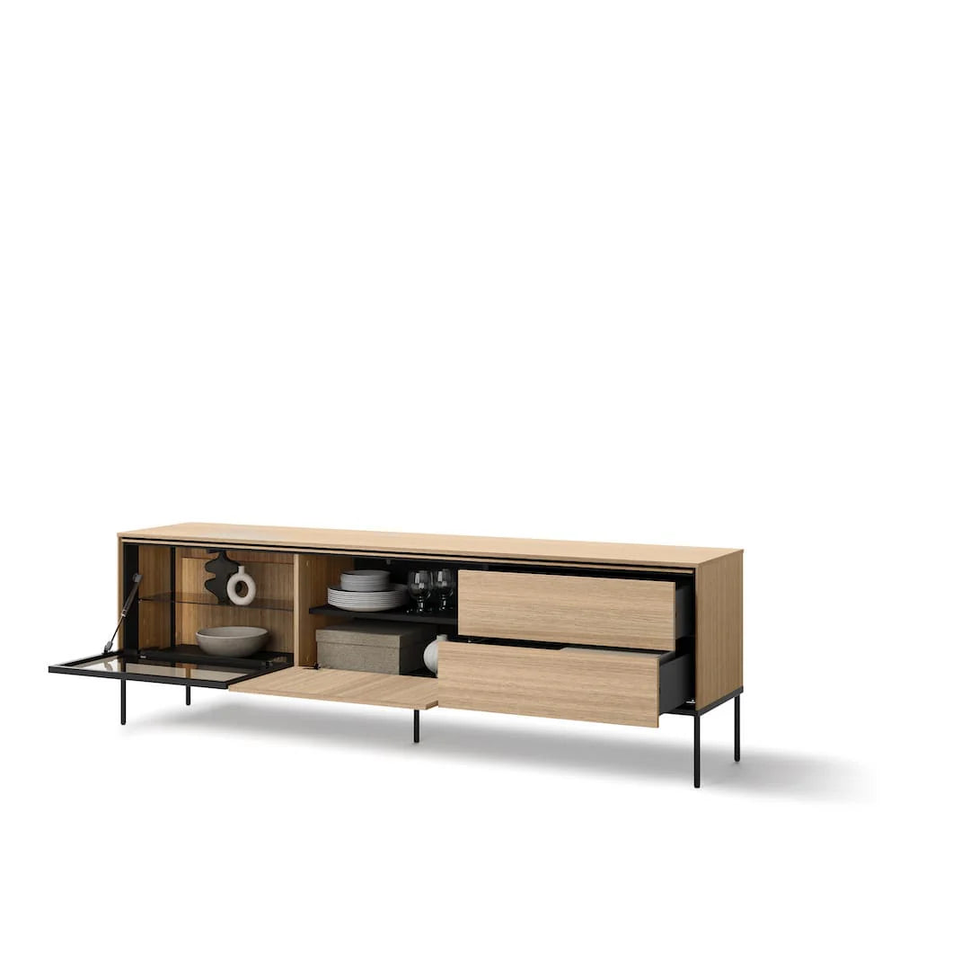 Light wood TV cabinet with open media shelf and drawers, black legs; dishware visible inside