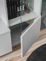 Media wall unit corner detail with open glass shelf, books, and white cabinet panels