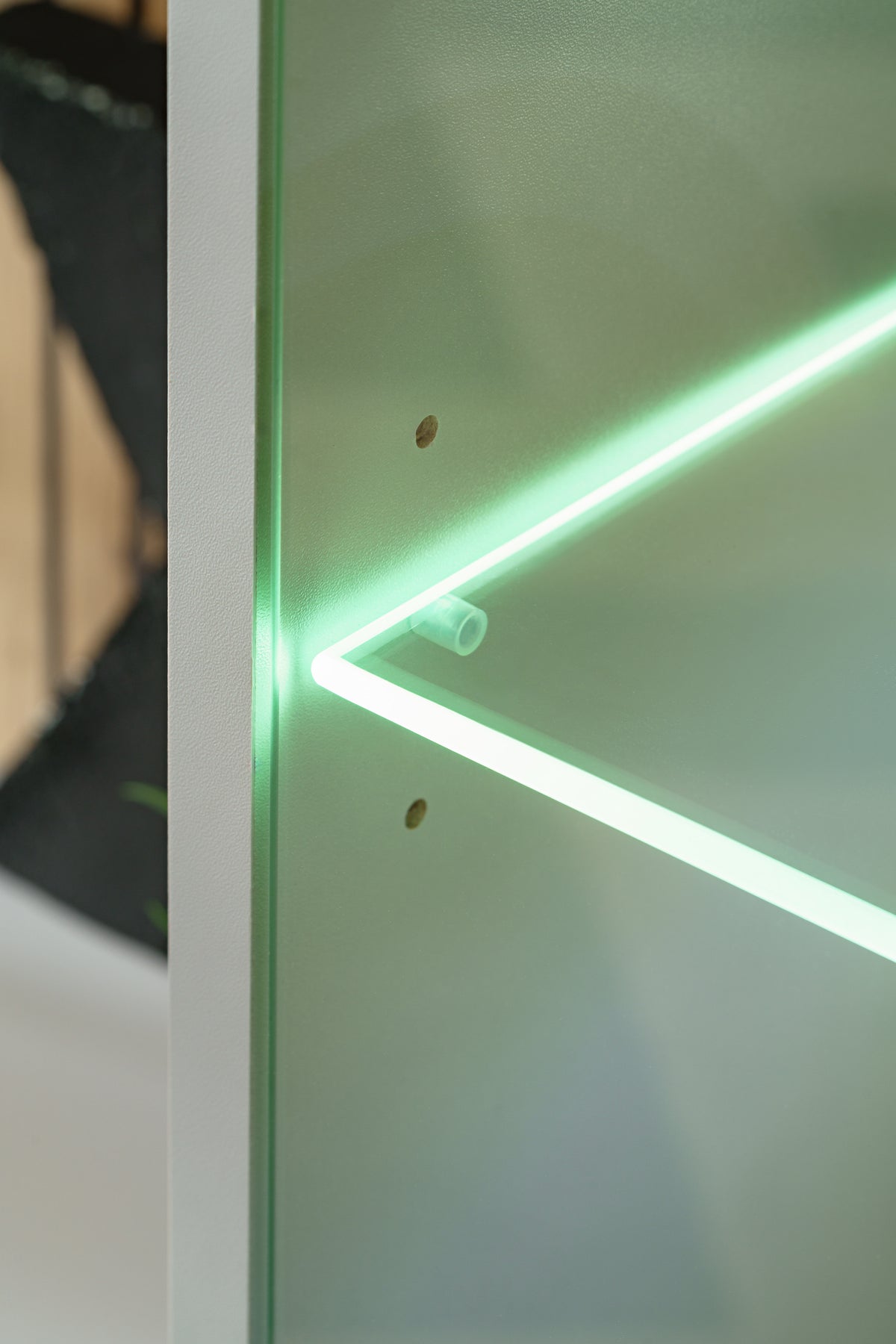 LED-lit glass shelf detail on Givi media wall unit with green light strip