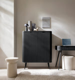Black highboard cabinet with vertical ribbed doors and tapered legs in a living room