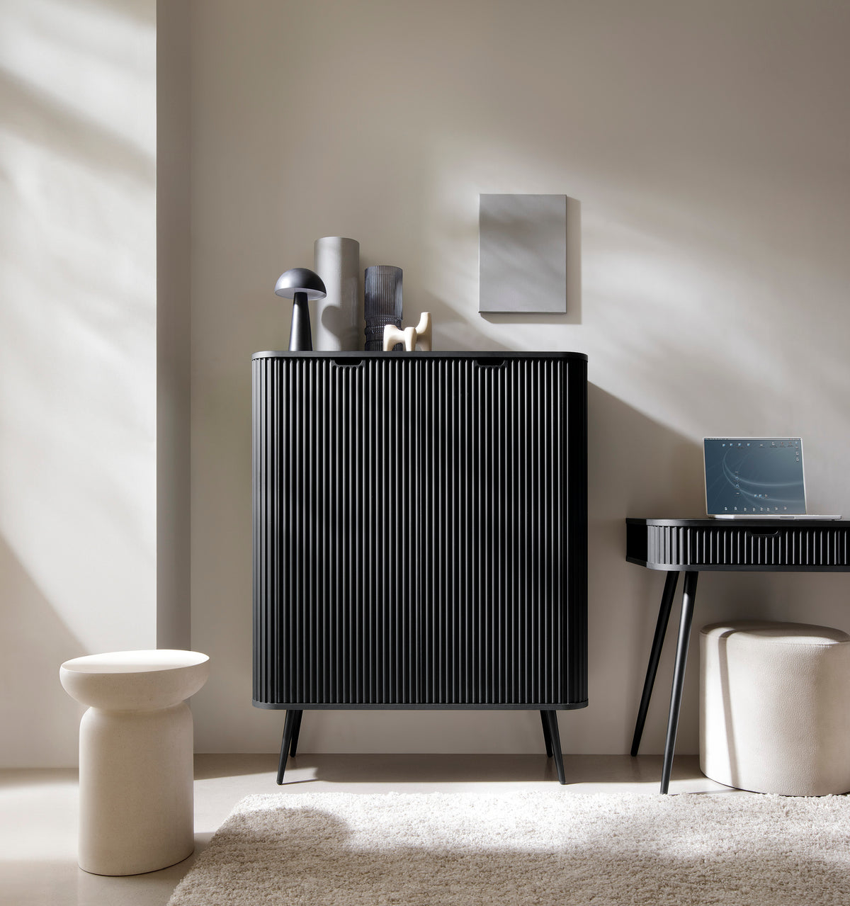 Black highboard cabinet with vertical ribbed doors and tapered legs in a living room