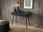 Black dressing table with striped drawer front and black tapered legs in a room setup