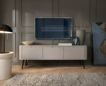 Mila TV cabinet in dark color with fluted fronts and four slim legs, styled in a living room.