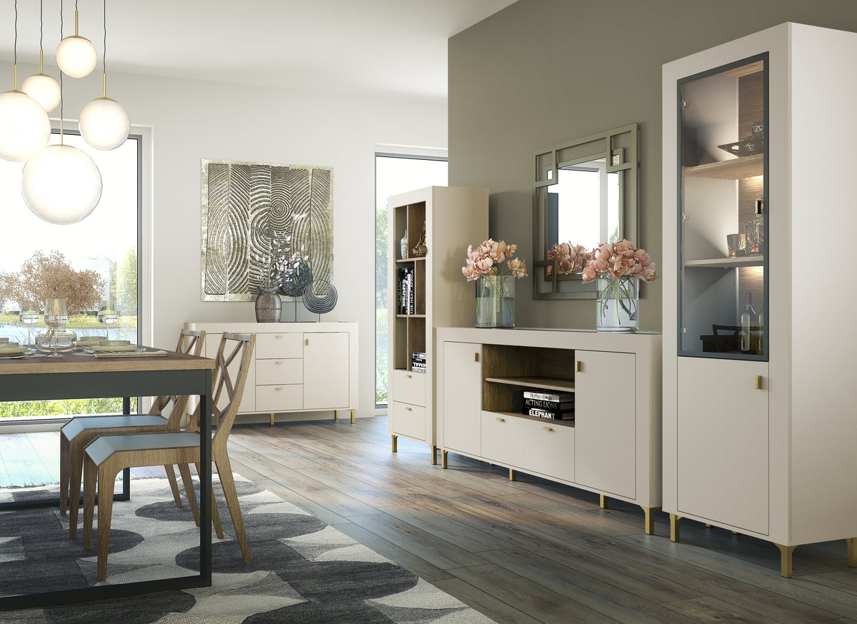 White bookcase with open cubby shelves and two lower drawers, gold feet.
